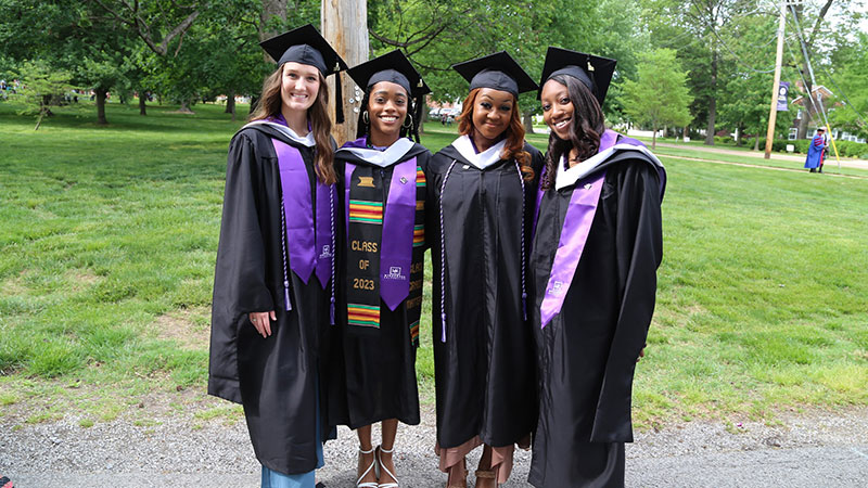 Four students posing in cap and gown